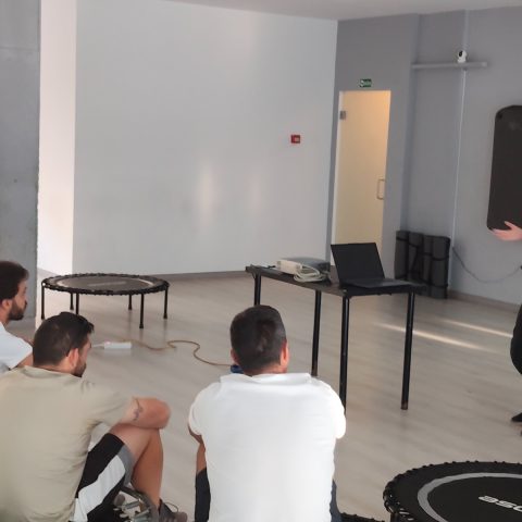 Formadora apresenta conteúdos a um grupo de participantes sentados em círculo durante uma ação de capacitação do projeto FIT - Fitness Inclusivo para Todos.
